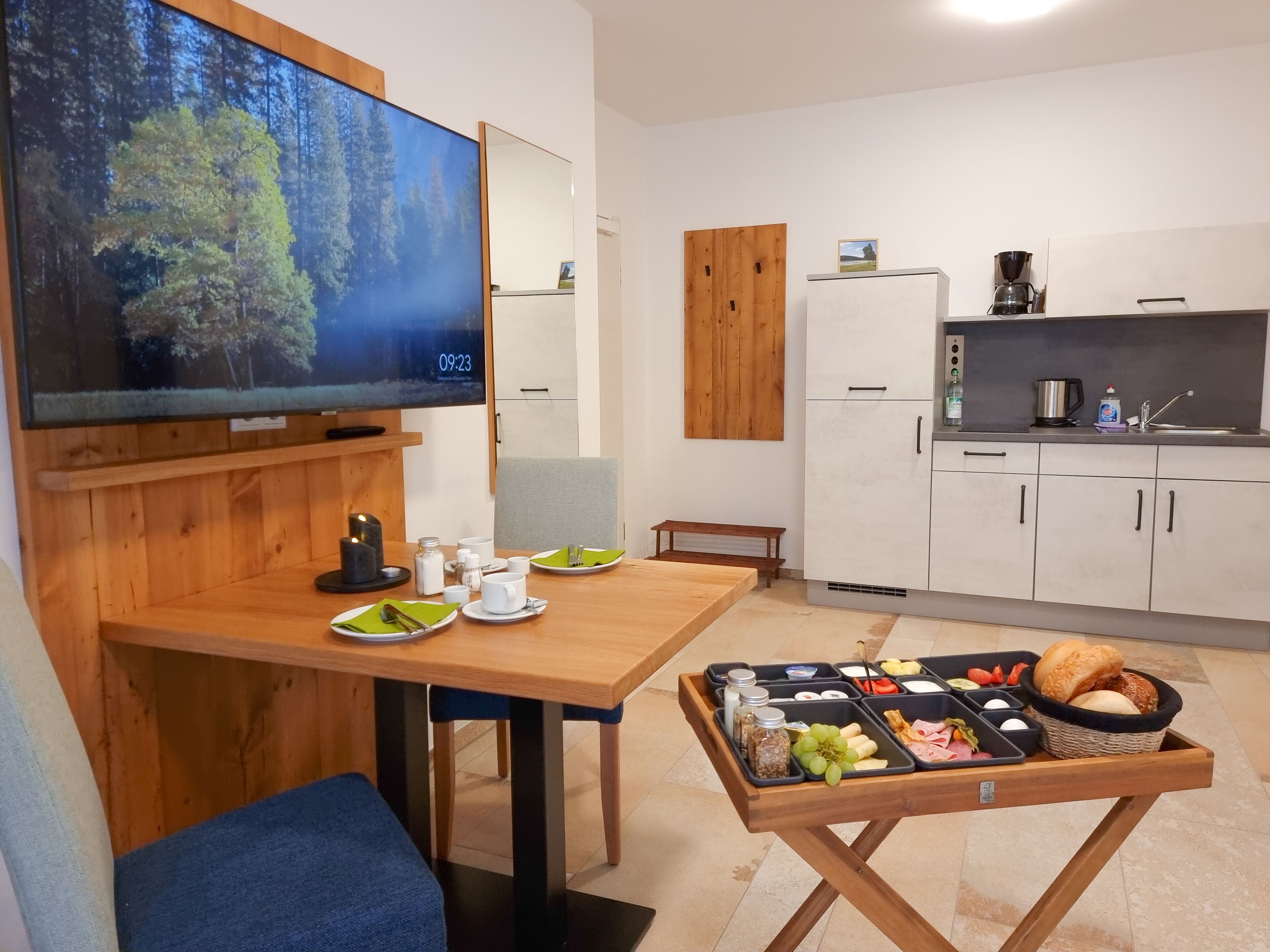 Eine moderne Küche mit weißen Schränken, einem Holztisch und einem Frühstücksbuffet.