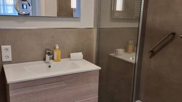 Un baño moderno con ducha de vidrio, tocador con espejo y retrete.