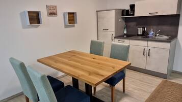 Een compacte keuken met een houten tafel en stoelen, een inbouwoven en een spoelbak.