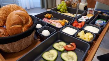 A breakfast buffet with various food items including bread, fruits, cheeses, and spreads.