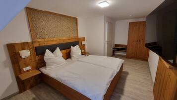 Ein Schlafzimmer mit einem hölzernen Bett, weißer Bettwäsche, einem Kopfteil mit Strukturpaneel, einem Nachttisch und einer Bank in der Ecke.