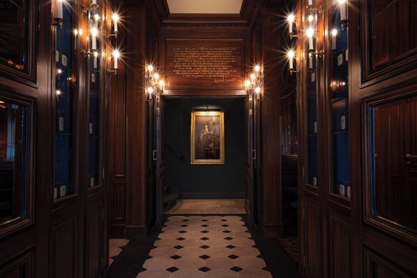 A hallway with wooden paneling, a patterned floor, and wall-mounted lights. - Maison Proust, Hotel & Spa La Mer (Paris)