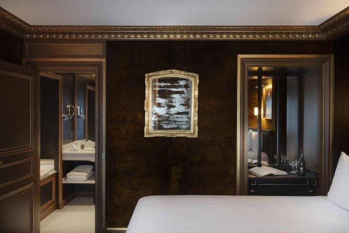 Ein Hotelzimmer mit einem großen Bett, einem Spiegel, einem gerahmten Bild an der Wand und einem Kleiderschrank.
