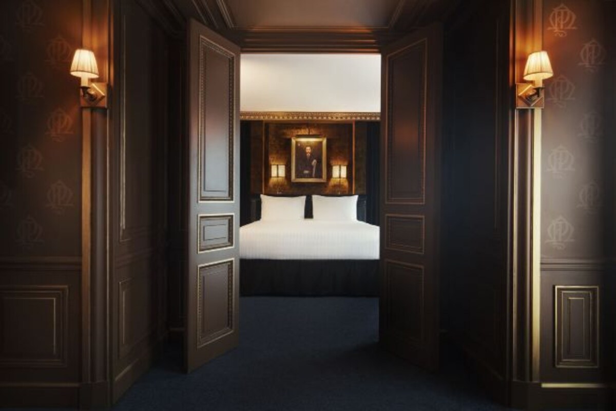 A bedroom with a bed, two wall-mounted lamps, and a framed picture above the bed.