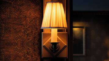 A wall-mounted lamp with a pleated shade, a geometric base, and a textured wall backdrop.