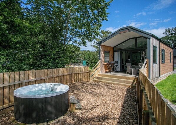 Une cabane en bois dotée d’un bain à remous, d’une terrasse et d’un patio couvert.