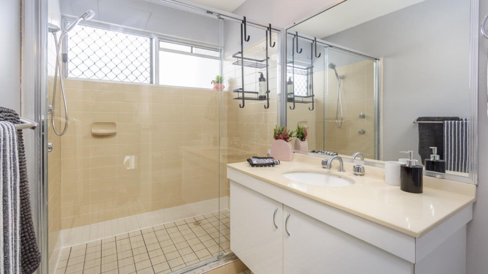 A modern bathroom with a glass shower enclosure, a large mirror, and a vanity with two sinks.