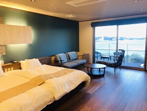 Ein Hotelzimmer mit einem großen Bett, einem Schlafsofa, einem kleinen Tisch und einem Balkon mit Aussicht.
