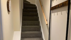 Una escalera con peldaños alfombrados que conduce a una puerta con perchero.