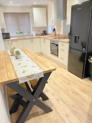 A modern kitchen with wooden flooring, a central island, and a black refrigerator.