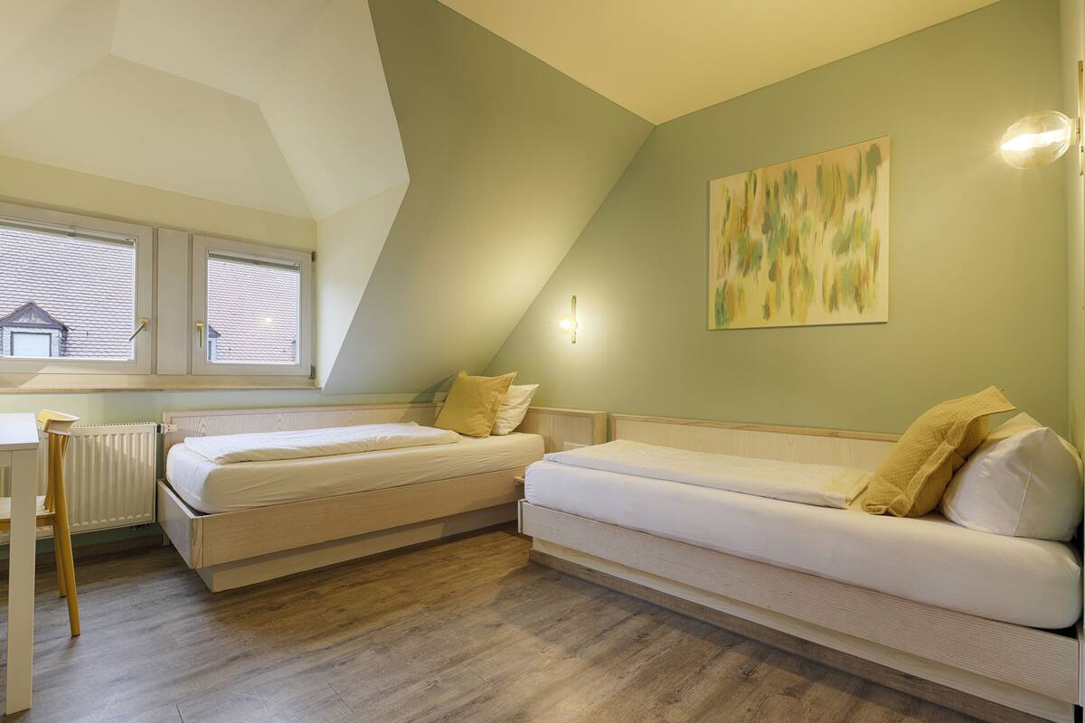 A room with two beds, a desk, and a radiator.