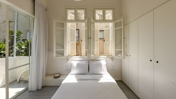 A bedroom with a large bed, a sliding glass door leading to a balcony, and a wardrobe. - Modern & Bright 3BR apt with 2Balconies (Tel Aviv)