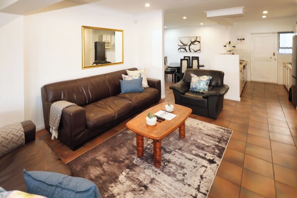 A living room with a brown leather sofa, a wooden coffee table, and a patterned rug.