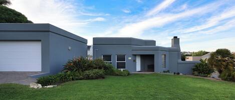A modern two-story house with a garage, a well-maintained lawn, and a clear sky.