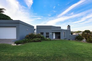 A modern two-story house with a garage, a well-maintained lawn, and a clear sky.