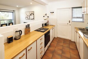 Cozinha compacta com bancada de madeira, fogão, cafeteira e pia.