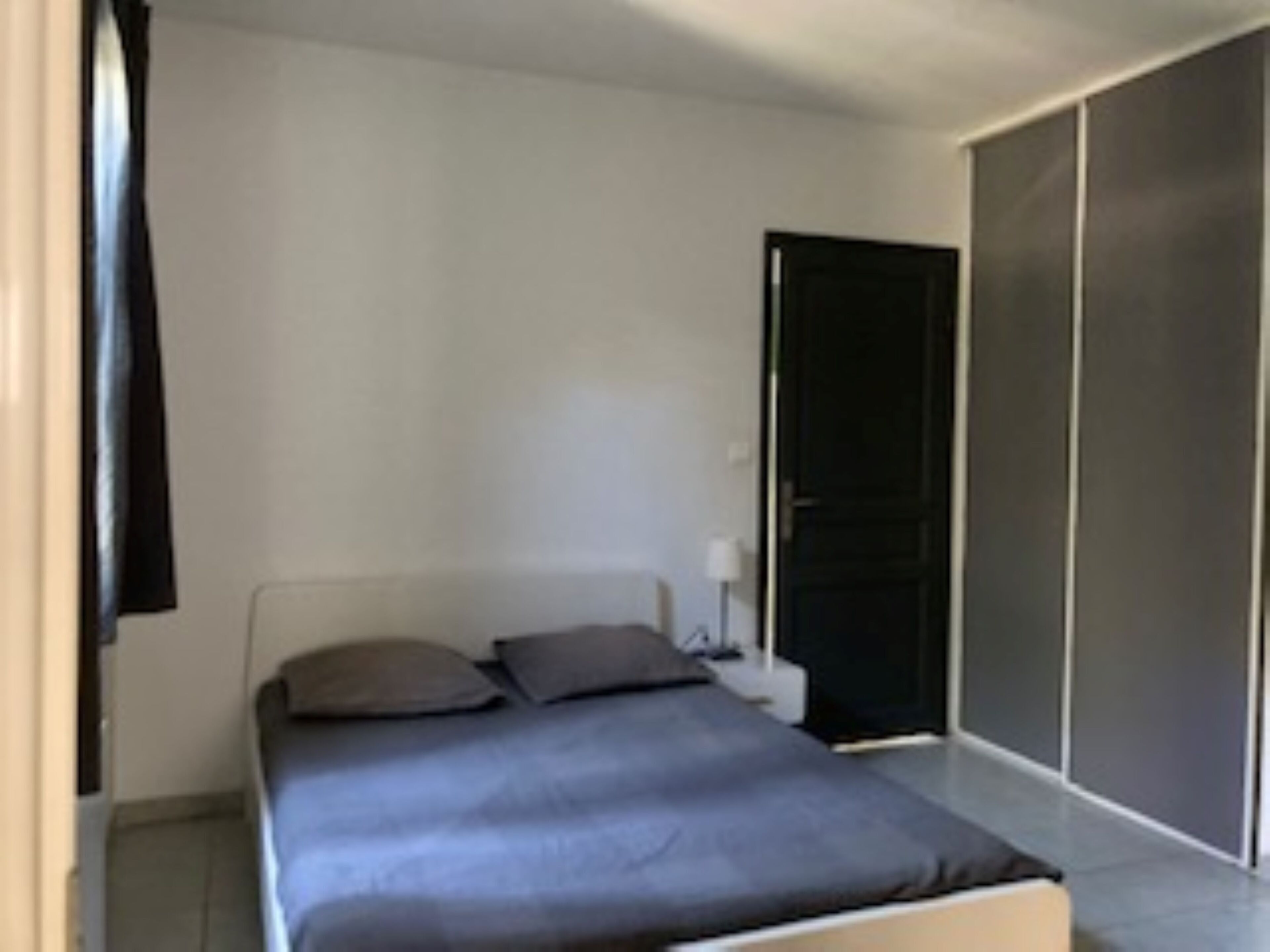 A bedroom with a bed, a nightstand, and a wardrobe.