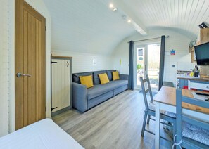Quarto compacto com sofá, mesa de jantar e televisão.