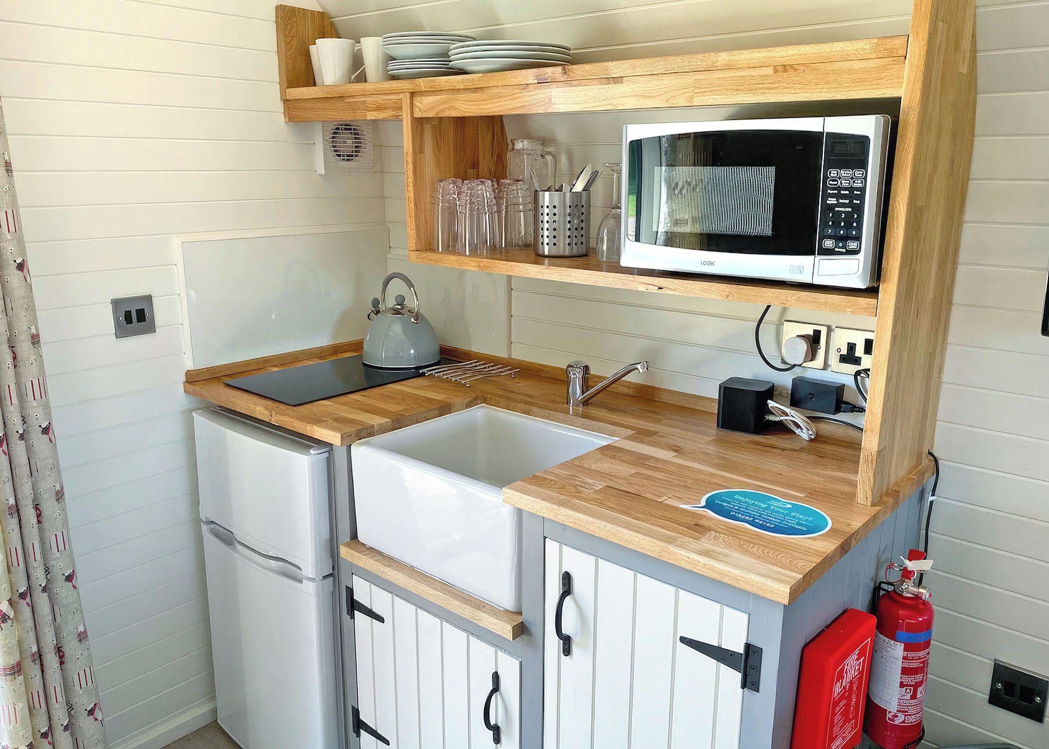A compact kitchen with a sink, a kettle, a microwave, and a refrigerator.