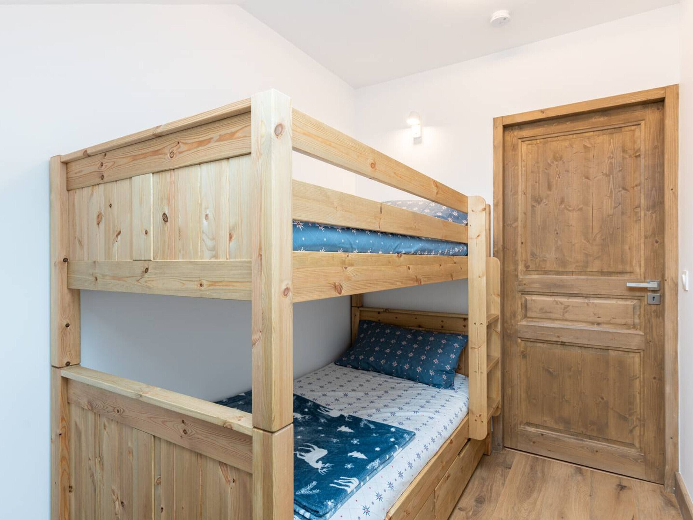 A bunk bed with a wooden headboard and a door to the right.