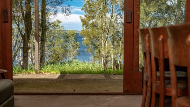 A wooden door leading to a view of a lake surrounded by trees. - Chill Out - couples retreat on the lake - short drive to Seal Rocks (Bungwahl)