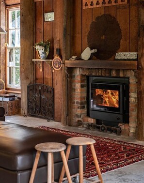 Ein rustikales Interieur mit Kamin, Holzwänden, einem gemusterten Teppich und einer Bank.