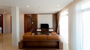 Una sala de estar moderna con un sofá, un televisor de pantalla plana y una pared de acento de mármol.