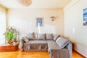 Un salon avec un canapé d’angle, une plante en pot et une œuvre d’art encadrée accrochée au mur.
