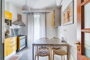Una cocina compacta con estufa, gabinetes amarillos y un comedor con mesa y sillas.