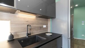 Una cocina moderna con un lavamanos de acero inoxidable, un horno empotrado y un refrigerador.