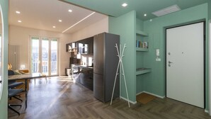Una cocina moderna con refrigerador, piso de madera y un comedor con sillas y una mesa.