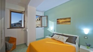 Ein Schlafzimmer mit Bett, Fenster, Sessel und einem Bild an der Wand.