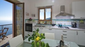 Eine Küche mit Meerblick, ein Esstisch mit Stühlen und ein Balkon mit einem Sessel.