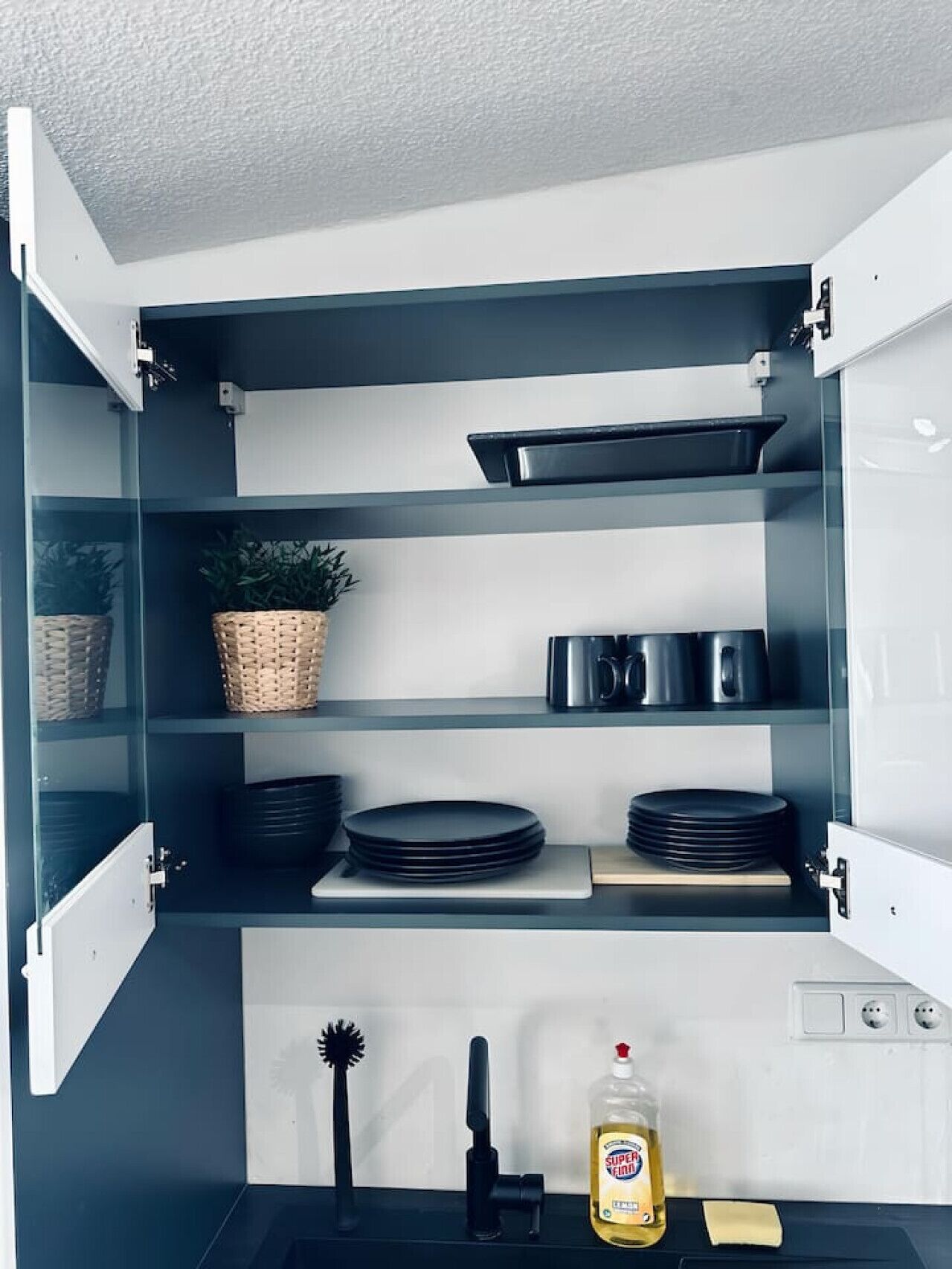 Ein Küchenschrank mit Regalen, der Teller, eine Pflanze und Küchenutensilien enthält.
