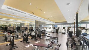 Et fitnesscenter med træningsudstyr, spejle og et stort vindue.