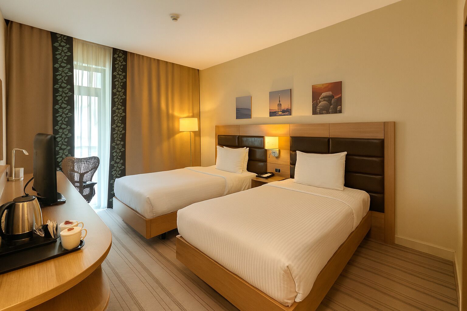 Une chambre d’hôtel avec deux lits, un bureau avec une machine à café, une chaise et un téléviseur.