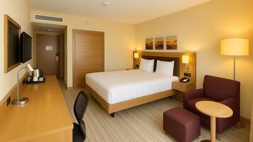 A hotel room with a bed, desk, chair, and a small table.
