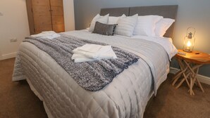 Una cama bien hecha con una colcha azul y blanca, un armario de madera, un adorno con forma de estrella y una pared con un letrero que dice 'sueños dulces'.
