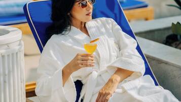 Guests can enjoy a refreshing drink by the pool, surrounded by lush greenery and a dining area.