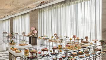A spacious room with a long table displaying various food items, a bicycle, and a decorative ceiling.