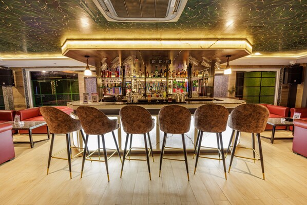 A bar area with a bar counter, multiple stools, and a seating area with couches and tables.