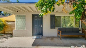 A residential house with a dark blue door, a small porch with a bench, and a large window. - Bright & Cozy Mid Town Zen Yard Studio! (Phoenix)