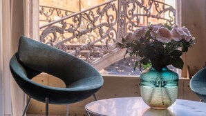 A round table with a vase of flowers, a modern chair, and a balcony railing. - Ninfea Luxury Suites (Venice)