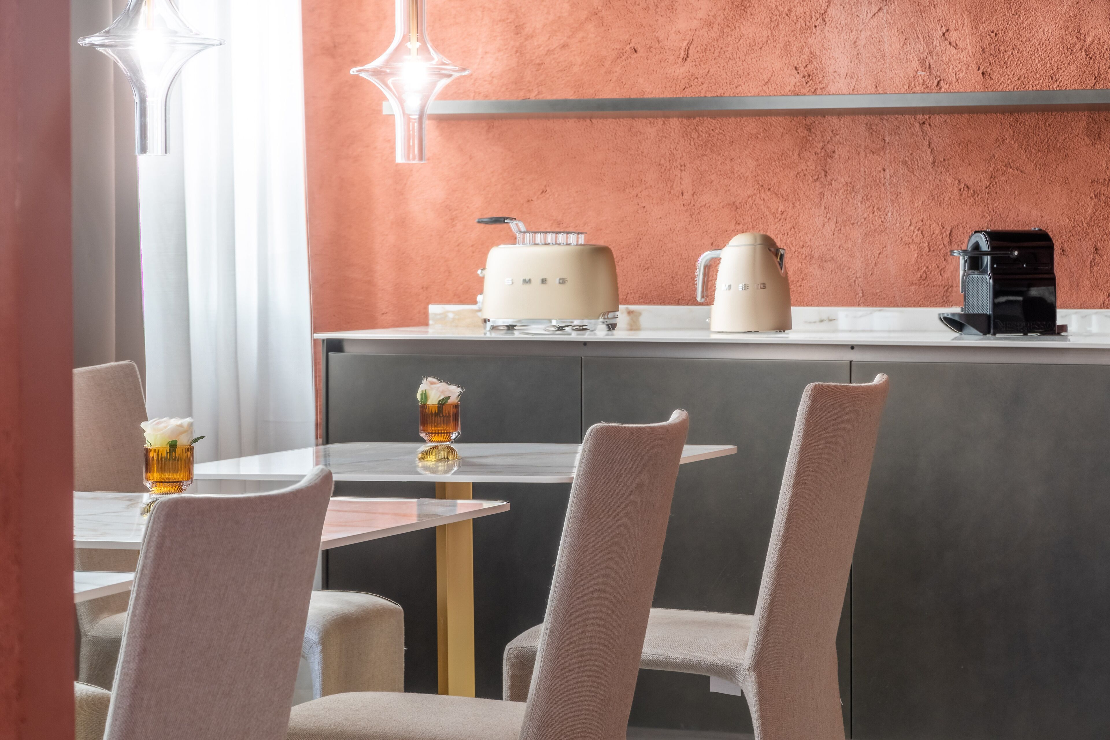 A modern dining area with a round table, two chairs, a coffee machine, and a toaster on a countertop.