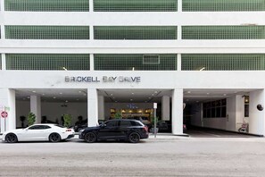 Un immeuble avec une enseigne indiquant « BRICKELL BAY DRIVE » et deux voitures garées devant.