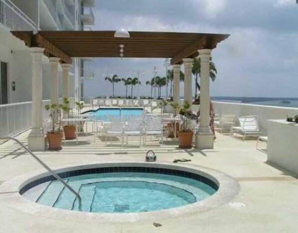 Relax by the ocean-view pool surrounded by a pergola and lush greenery.