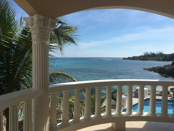 Un balcon avec vue sur l’océan et un espace piscine.