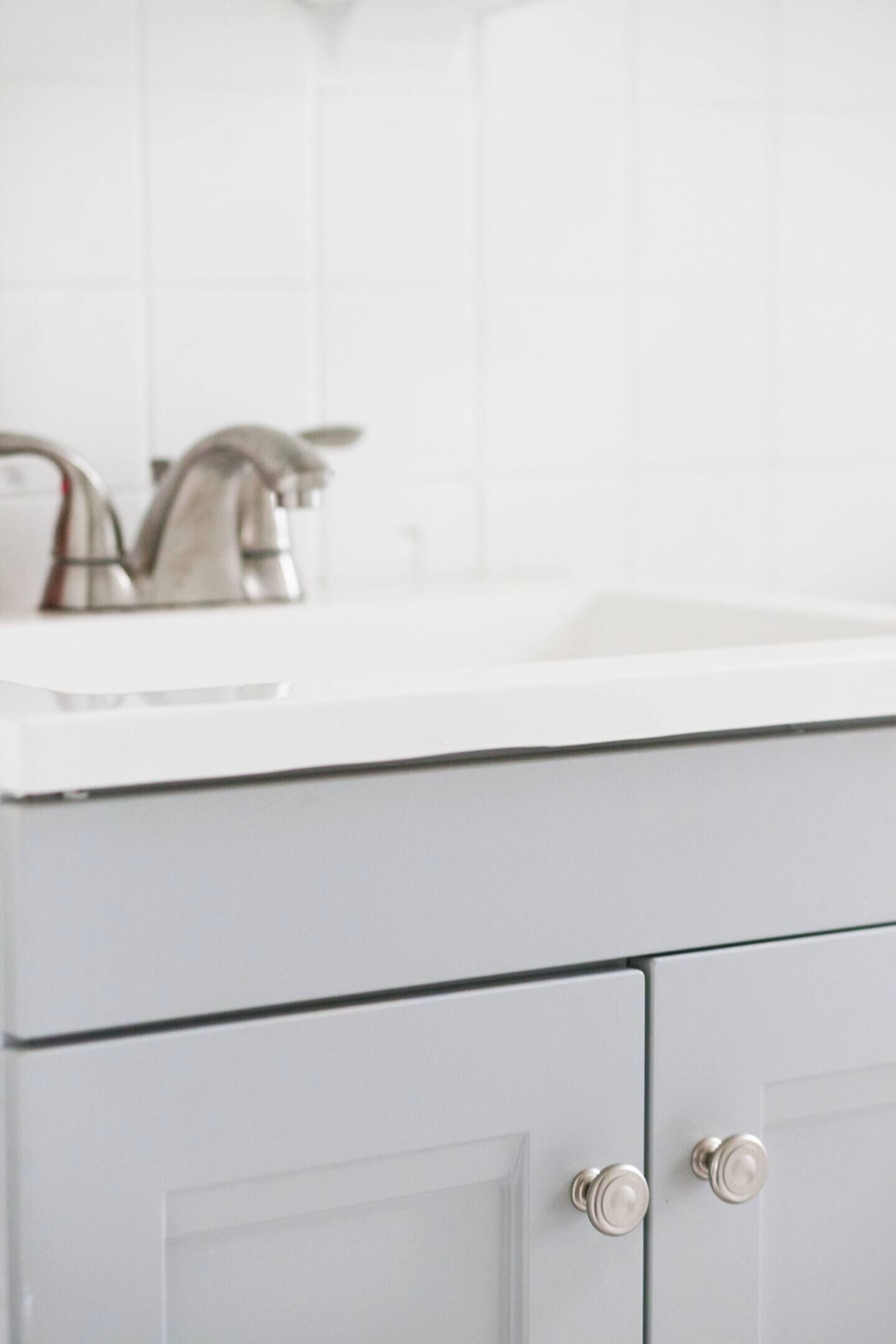 Un baño con lavamanos blanco, grifo plateado y muebles de tono claro.