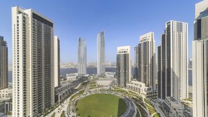 A modern high-rise residential area with multiple tall buildings, a central circular park, and a waterfront view. - WelHome - Luxe Apartment With Incredible View on Dubai Creek (Dubai)