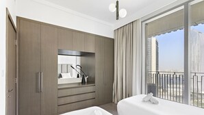 A hotel room with two beds, a large window with a view of tall buildings, a wardrobe, and a mirror. - WelHome - Luxe Apartment With Incredible View on Dubai Creek (Dubai)